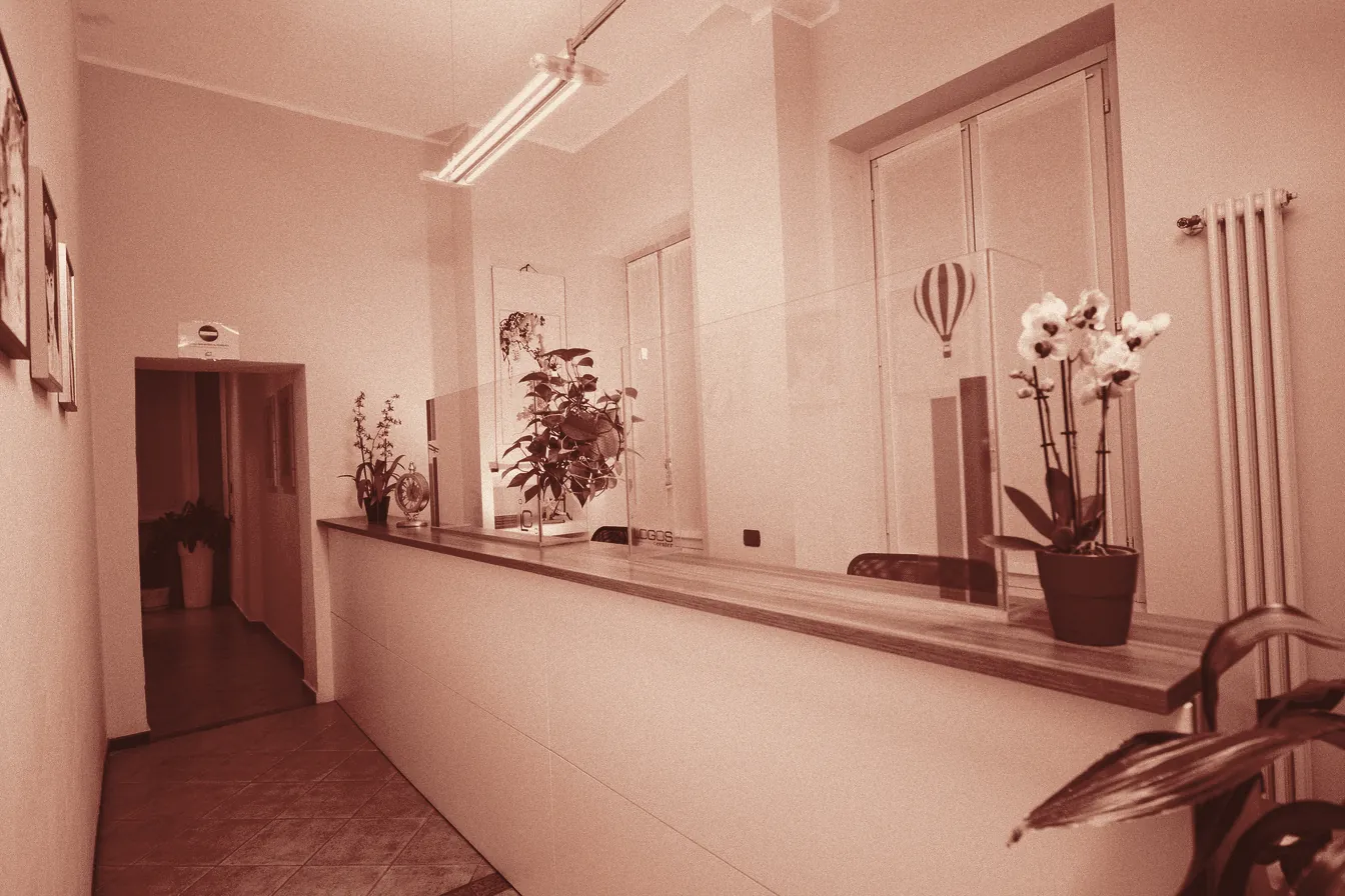 L'ingresso della sede: il bancone dell'accoglienza con le orchidee e la porta verso gli uffici
